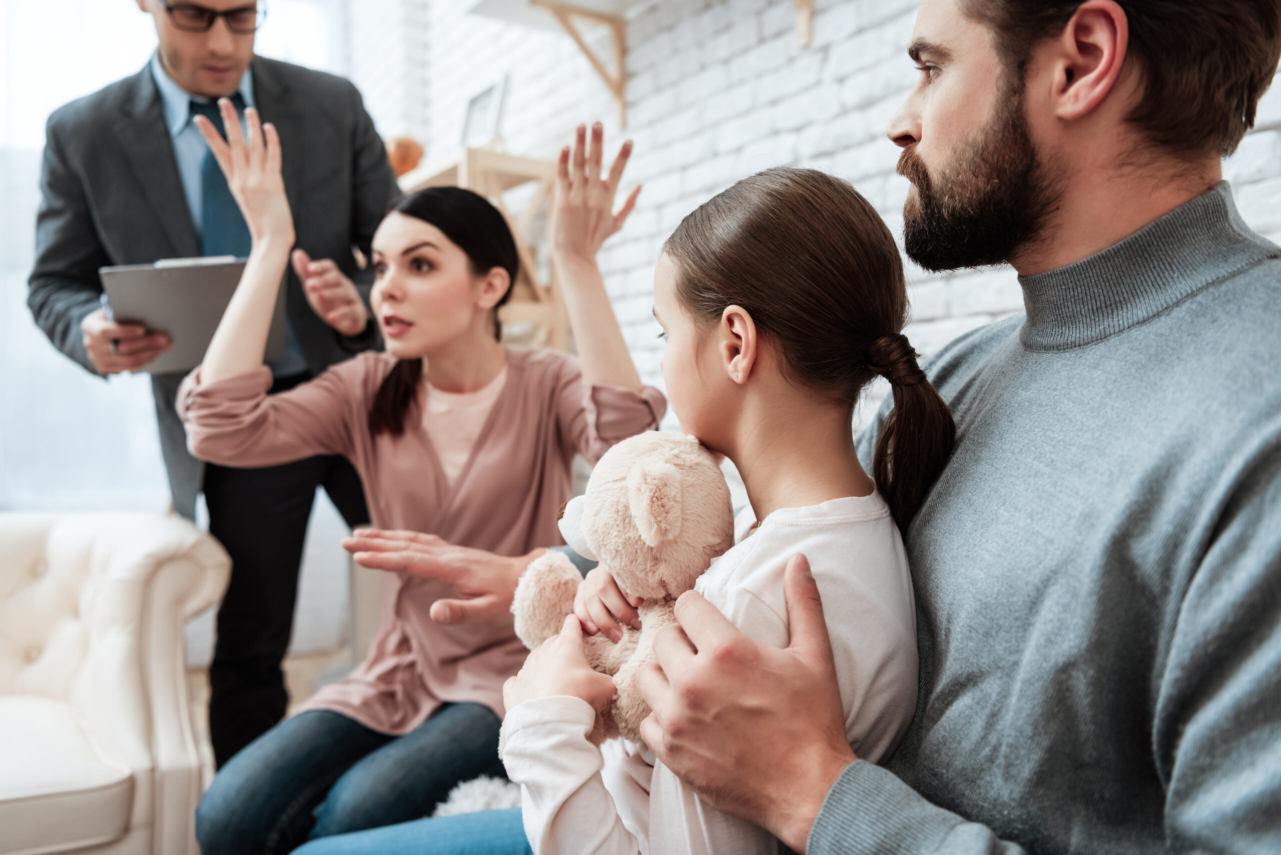 Father and daughter look at angered mother, who raised hands up in office of family psychotherapist. Discussion of concern problems in family at psychologist office.